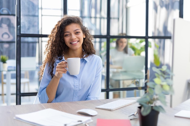 Beautiful businesswoman drinking coffee while working on computer Collegue is on the background