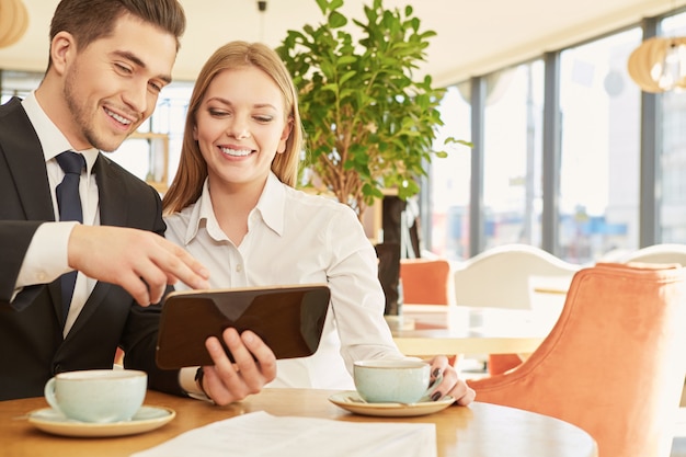 Beautiful businesswoman and her male colleague discussing projects over breakfast at cafe