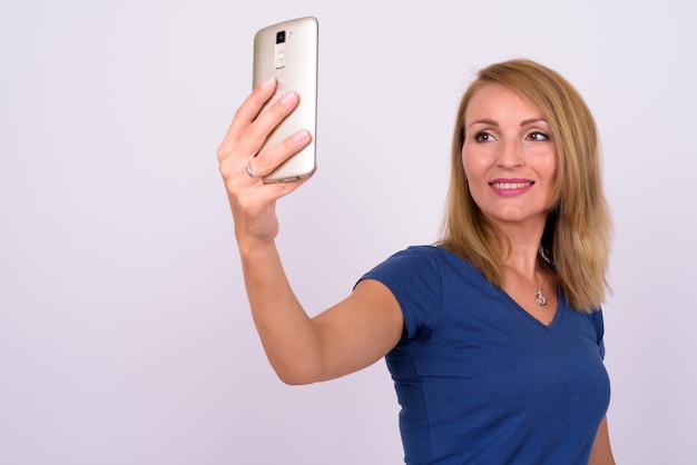  beautiful businesswoman with blond hair wearing blue shirt against white wall