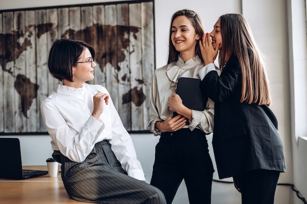 Beautiful businesswomen discuss and whisper to each other