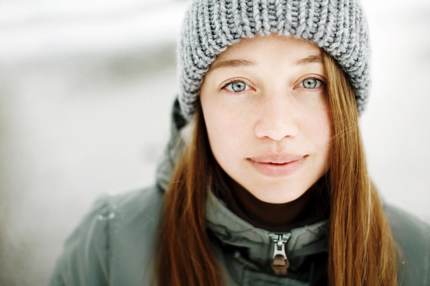 Beautiful calm smiling young woman in winter warm outfit posing outdoors in snowy park portrait