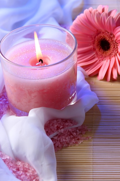 Beautiful candle with flower on white cloth close up