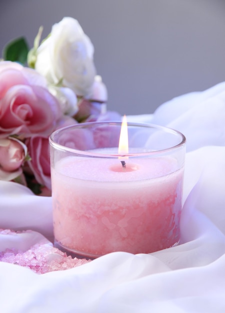 Beautiful candle with flower on white cloth, close up