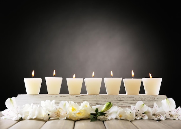 Beautiful candles with flowers on wooden background