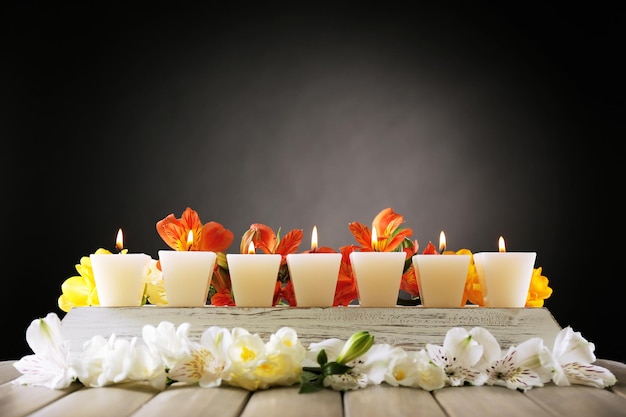 Beautiful candles with flowers on wooden background