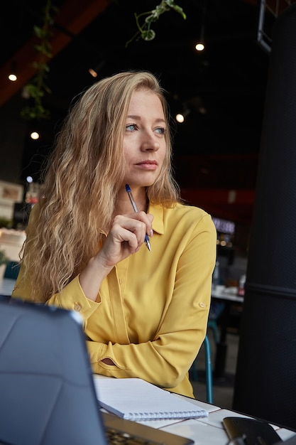 Beautiful caucasian business woman sitting indoors writing notes in notebook