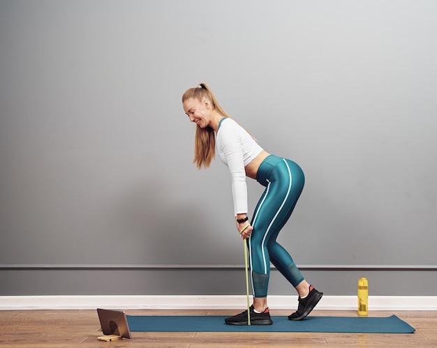 Beautiful caucasian girl working out at home. Brunette girl in squat position working out glutes.