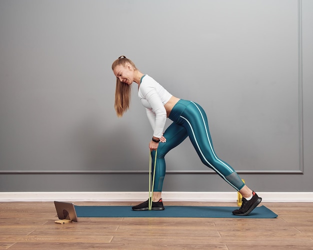 Beautiful caucasian girl working out at home. Brunette girl in squat position working out glutes.