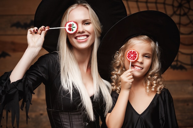 beautiful caucasian mother and her daughter in witch costumes celebrating Halloween with Halloween candy 