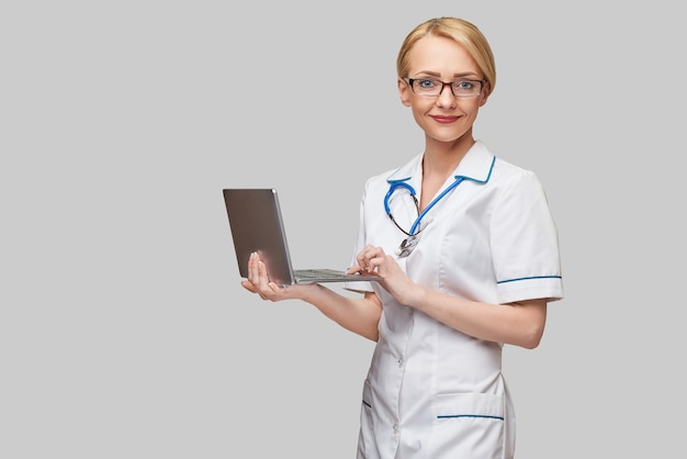 Beautiful Caucasian woman doctor or nurse holding a laptop pc computer