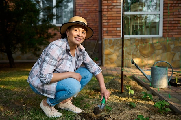 Beautiful Caucasian woman farmer agronomist using garden shovel digging soil and making a hole for planting seedlings