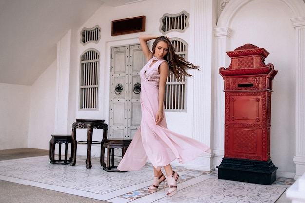 Beautiful caucasian woman in luxury evening pink dress and rich accessories 