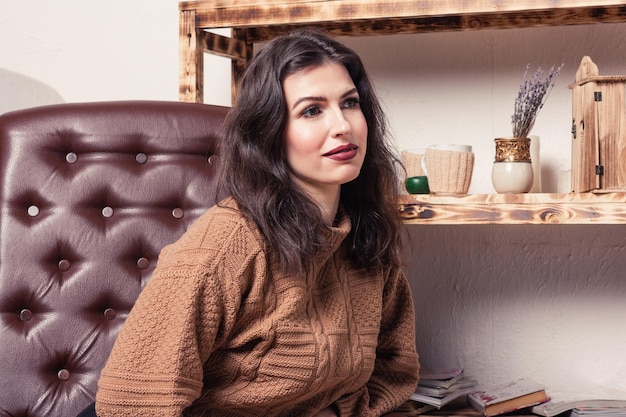 Beautiful caucasian young woman sits in a leather chair