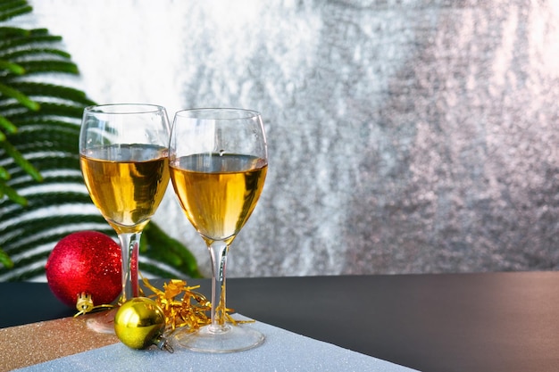 Beautiful champagne glasses with Christmas decorations and shiny silver background