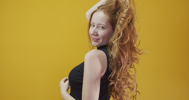 Beautiful cheerful redhead girl smiling laughing looking at camera over yellow background.