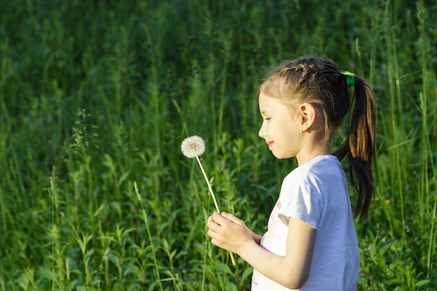 Beautiful child blowing away dandelion flower in spring. Fun on meadow.