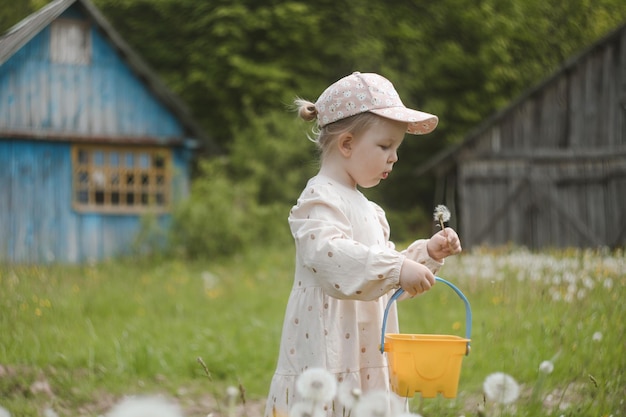 Beautiful child with dandelion flowers in park in summer Happy kid having fun outdoors