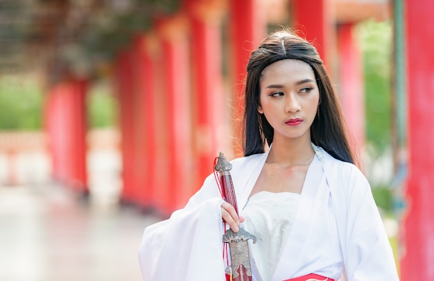 Beautiful Chinese woman with a traditional suit with a sharp sword in her hands.