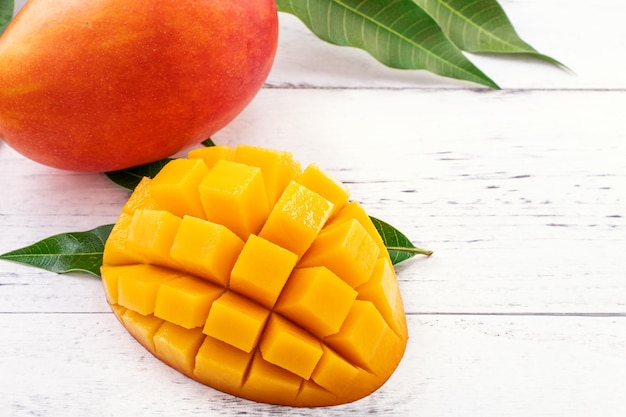 Beautiful chopped mango with green leaves on bright white color timber background Above Top view flat lay copy space close up Tropical fruit concept