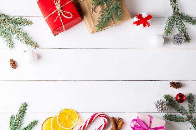 Beautiful Christmas composition on wooden white background with Christmas gift boxes,  dried fruits, holiday decoration, caramel stick. New Year.