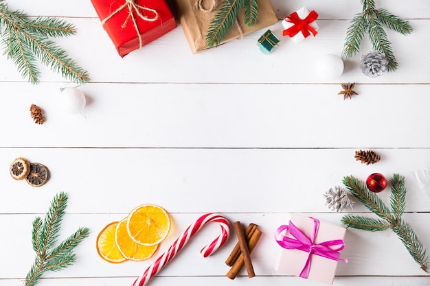 Beautiful Christmas composition on wooden white background with Christmas gift boxes, dried fruits, holiday decoration, caramel stick. New Year.