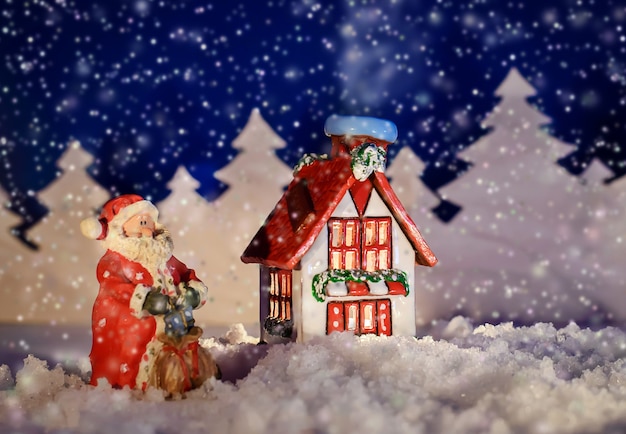 Beautiful Christmas fairy-tale picture of a house and Santa in the winter night in the snow