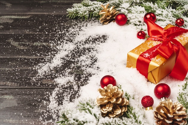 Beautiful Christmas gift with snowy holiday decorations on table