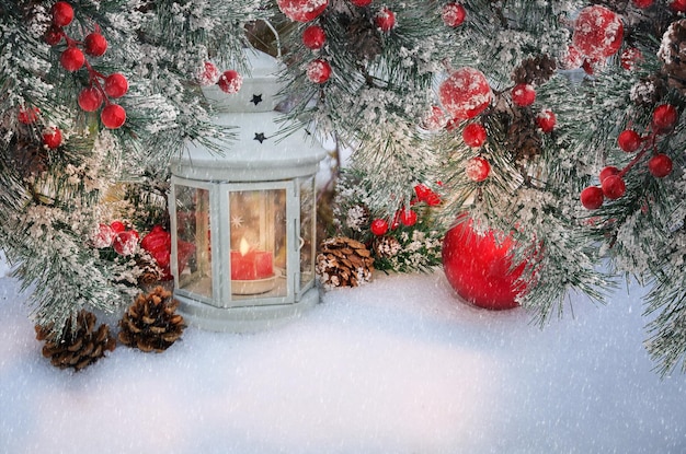 Beautiful Christmas lantern with candle and fir branches with cones and red berries