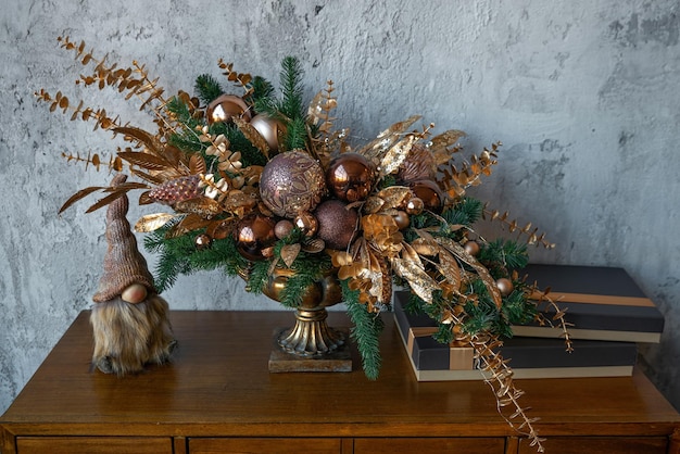 Beautiful Christmas and New Year decoration with golden and bronze deco baubles and fir branches in vintage vase. Xmas decoration ideas. Winter holidays concept.