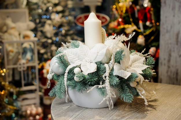 Beautiful Christmas table decorative composition with white candle, flowers and fir tree branches in white vase