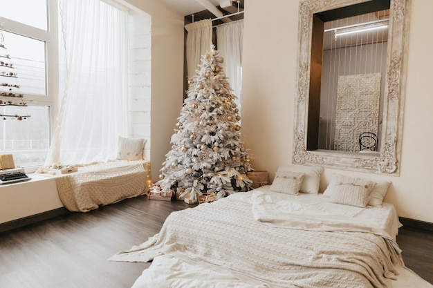 A beautiful Christmas tree in a decorated living room with a bed Festive interiorChristmas