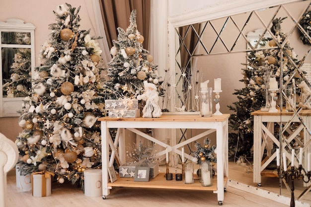 A beautiful Christmas tree stands in the living room near the table with New Years decor