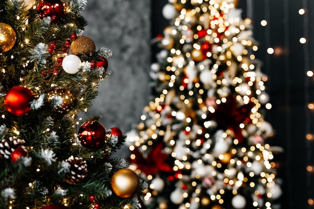 Beautiful Christmas tree with festive gold red decor against blurred lights on background closeup