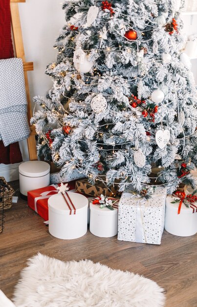 Beautiful Christmas tree with gift boxes in bright white living room.