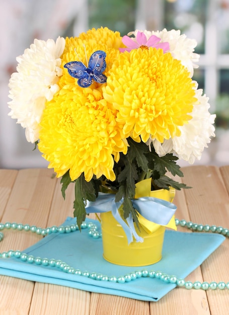 Beautiful chrysanthemum in pail on wooden table on window background