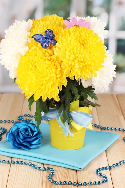 Beautiful chrysanthemum in pail on wooden table on window background