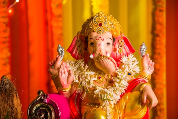 A Beautiful clay statue or Idol of an Indian Hindu god Lord Ganesha decorated with colourful drapery and Marigold garland  for ganesh Chaturthi festival celebration or pooja