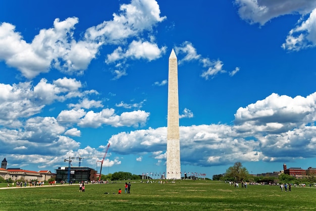 During the beautiful and cloudy day, the monument of american president George Washington was pictured. People and tourists enjoy a great day.