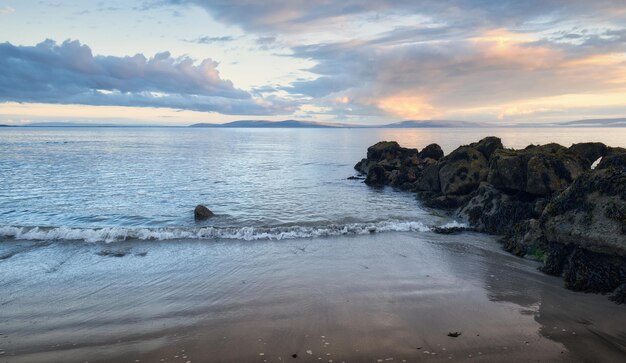 Beautiful coastal sunset landscape scenery with rocks and stones on sandy Salthill beach in Ireland