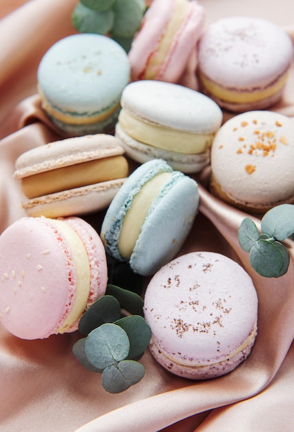 Beautiful colorful tasty macaroons and eucalyptus on a textile background