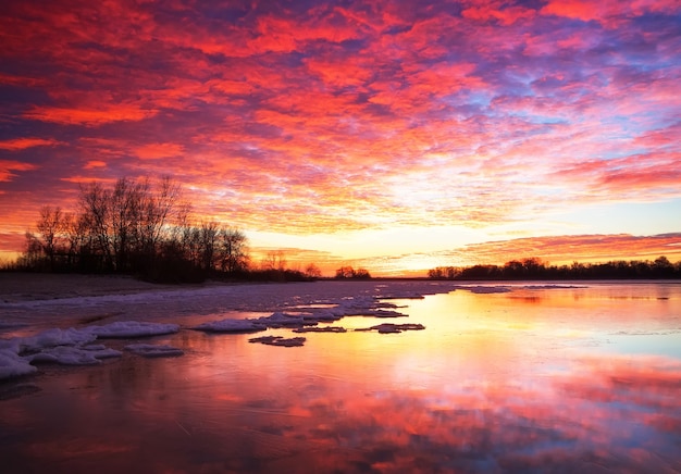 Beautiful colorful winter landscape with frozen lake and sunset sky. Unusual weather phenomenon