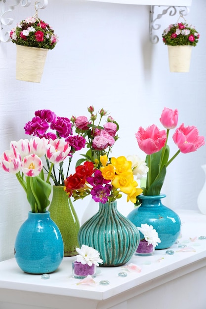 Beautiful composition with different flowers in vases on wall background