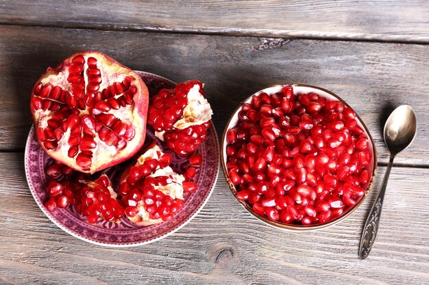 Beautiful composition with juicy pomegranate seeds on old wooden table