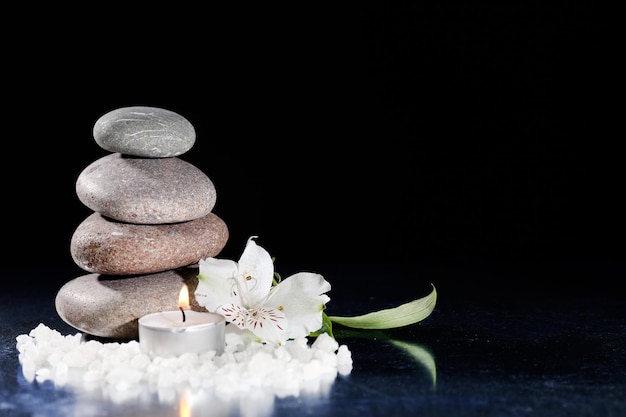 Beautiful composition with spa stones and candle on table on dark background