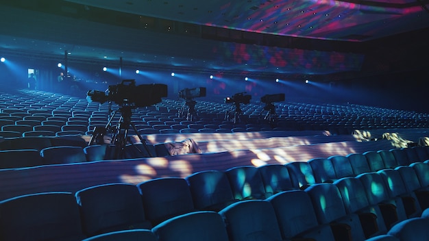 In a beautiful concert hall there are cameras aimed at the stage lighting in blue light