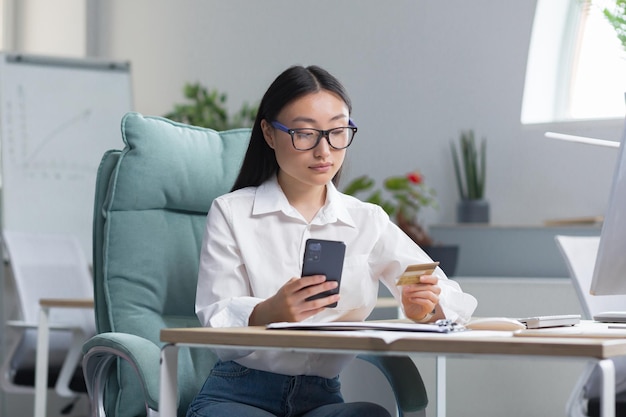 Beautiful and confident asian business woman working in the office making banking transactions using