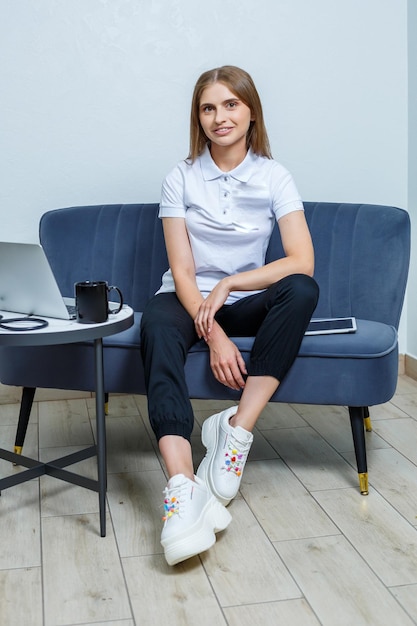 Beautiful confident female doctor general practitioner in a white medical uniform sits at a table in a hospital medical worker