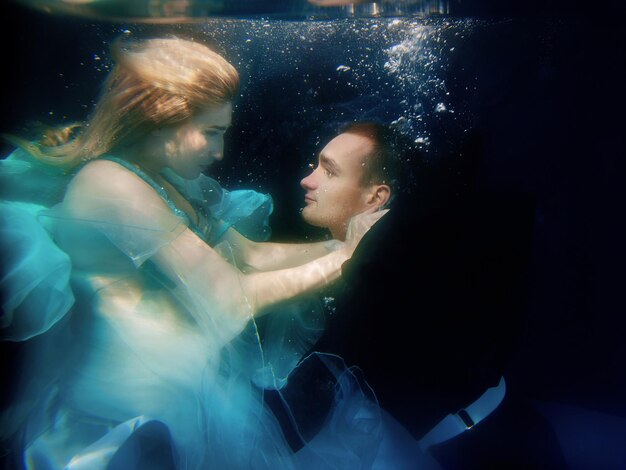 Photo beautiful couple dancing underwater in the swimming pool