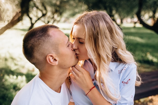 A beautiful couple is resting outside the city, sitting near a big tree in the garden