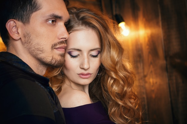 Beautiful couple in love hugging against the background of glowing lights.